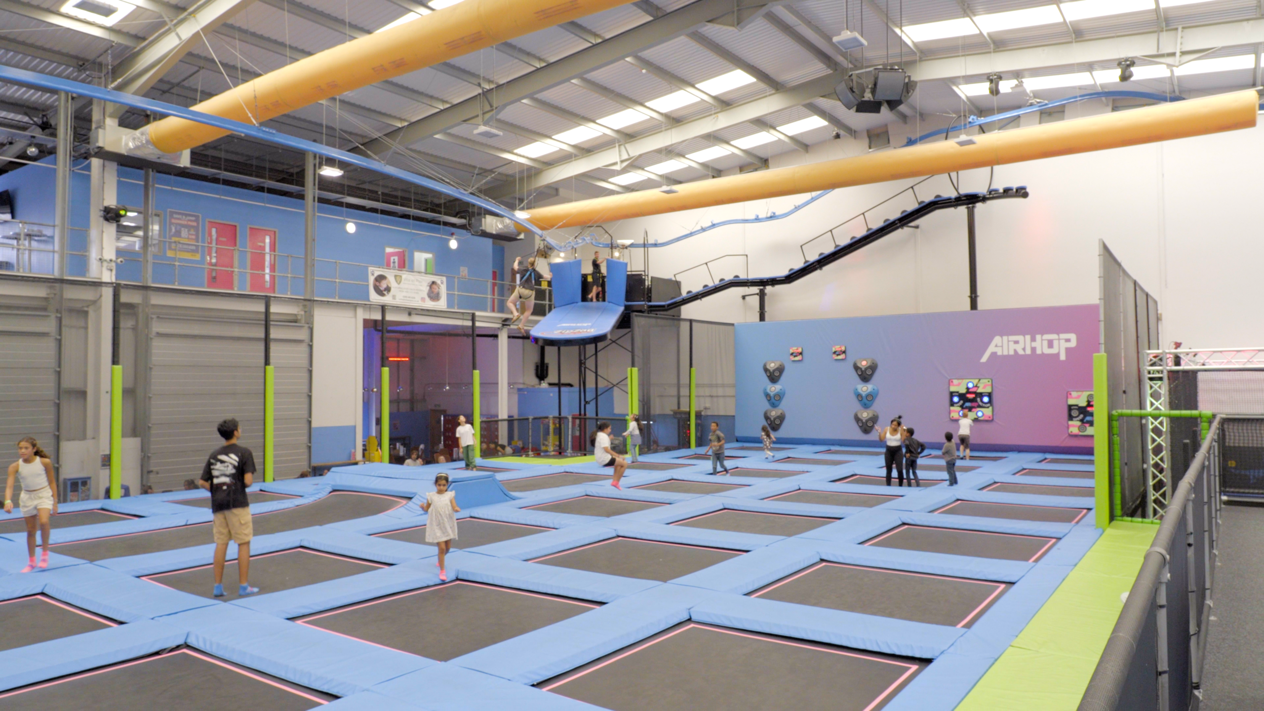 airhop-enfield-trampoline-park-with-airglider-zipcoaster-above View across the trampoline courts at AirHop Enfield with an AirGlider zipcoaster above
